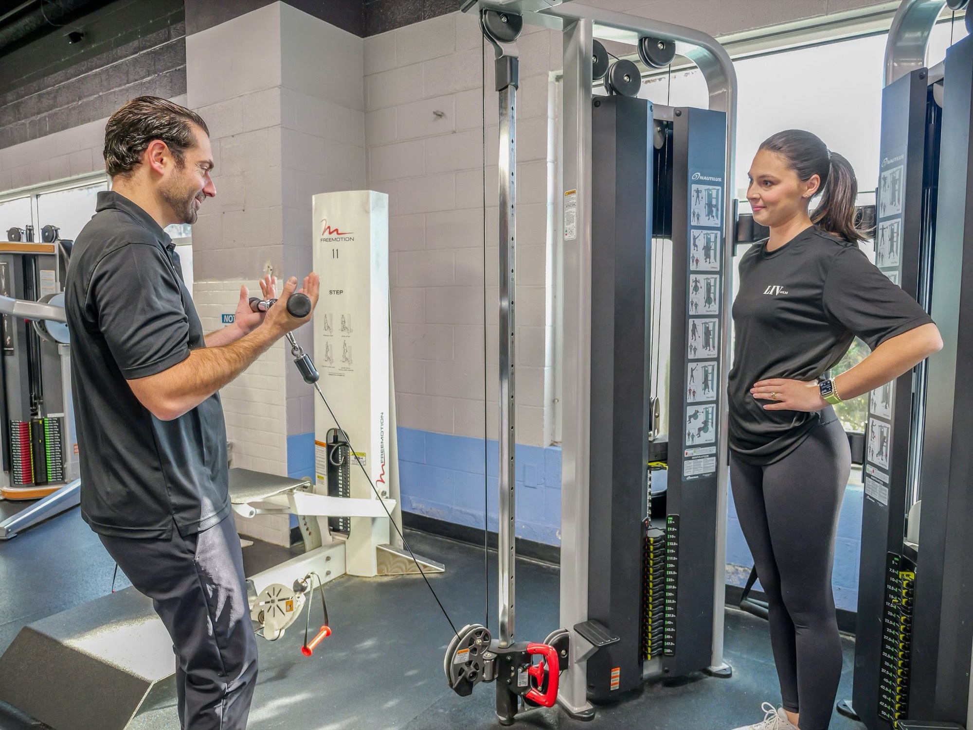 Two LIVunLtd team members talking beside strength machines in a fitness centre