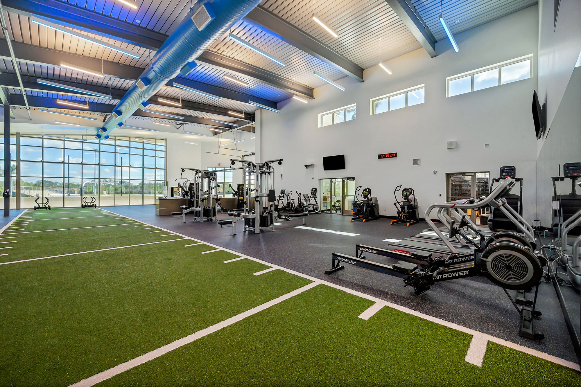Community field house with indoor turf lanes, rowing machines and an exposed blue steel roof