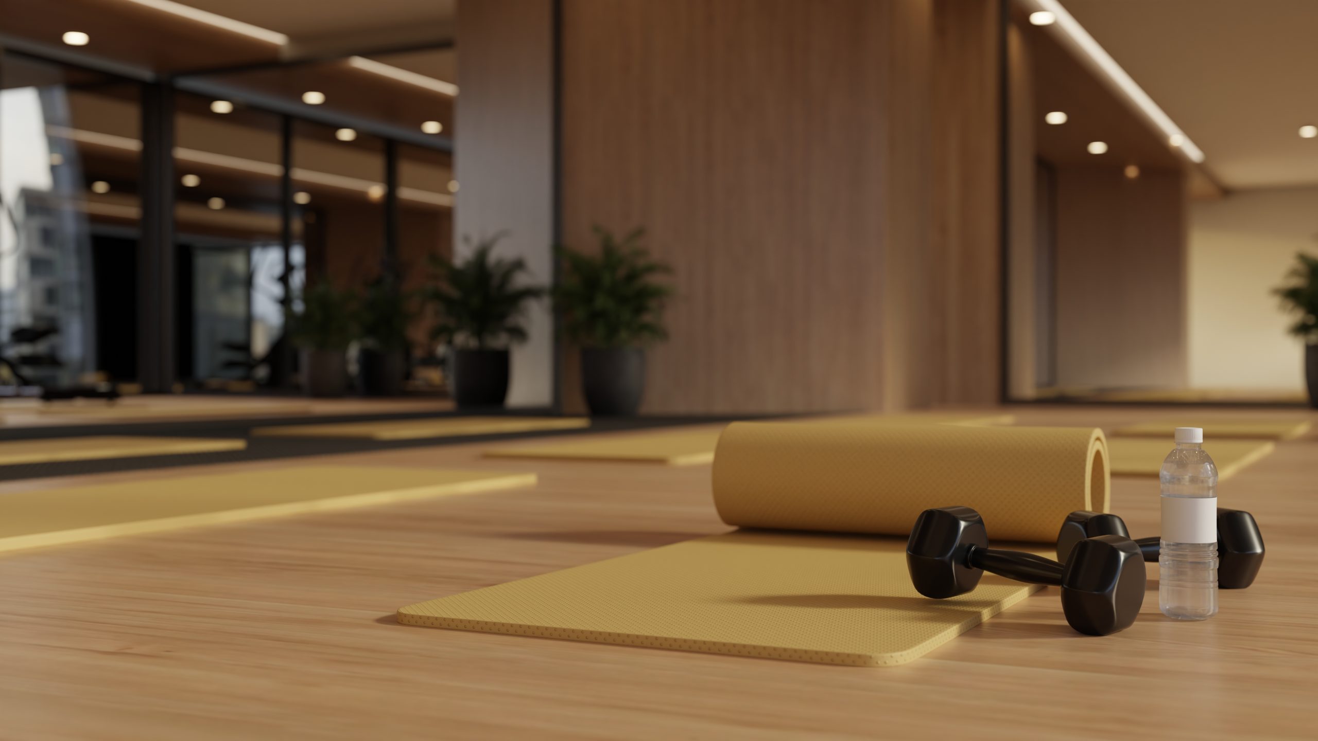 Group fitness studio with rolled yoga mats, dumbbells and a water bottle on a wood floor