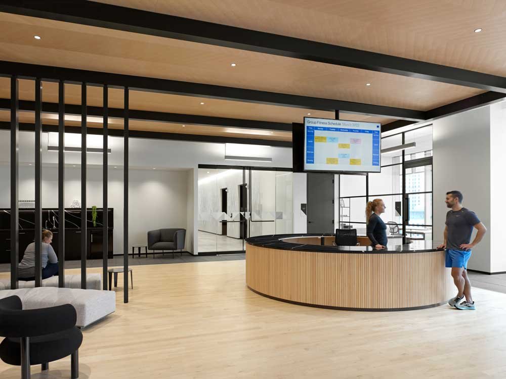 Modern fitness center lobby with a curved reception desk and wall-mounted screen