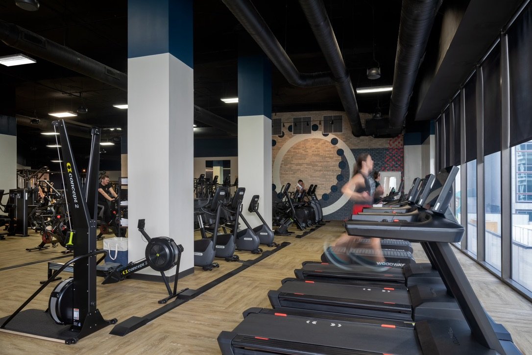 Cardio and strength equipment in a gym with dark accent walls