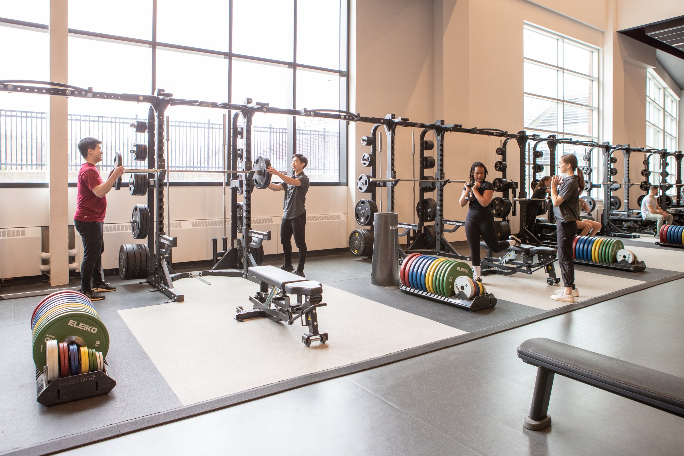 Members training on squat racks and platforms in a student fitness center