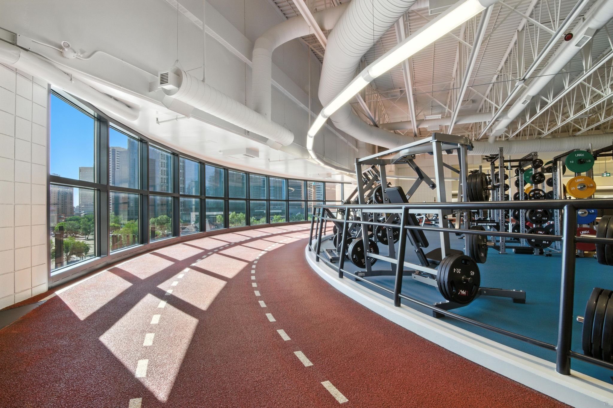 Indoor running track curving past a strength training floor
