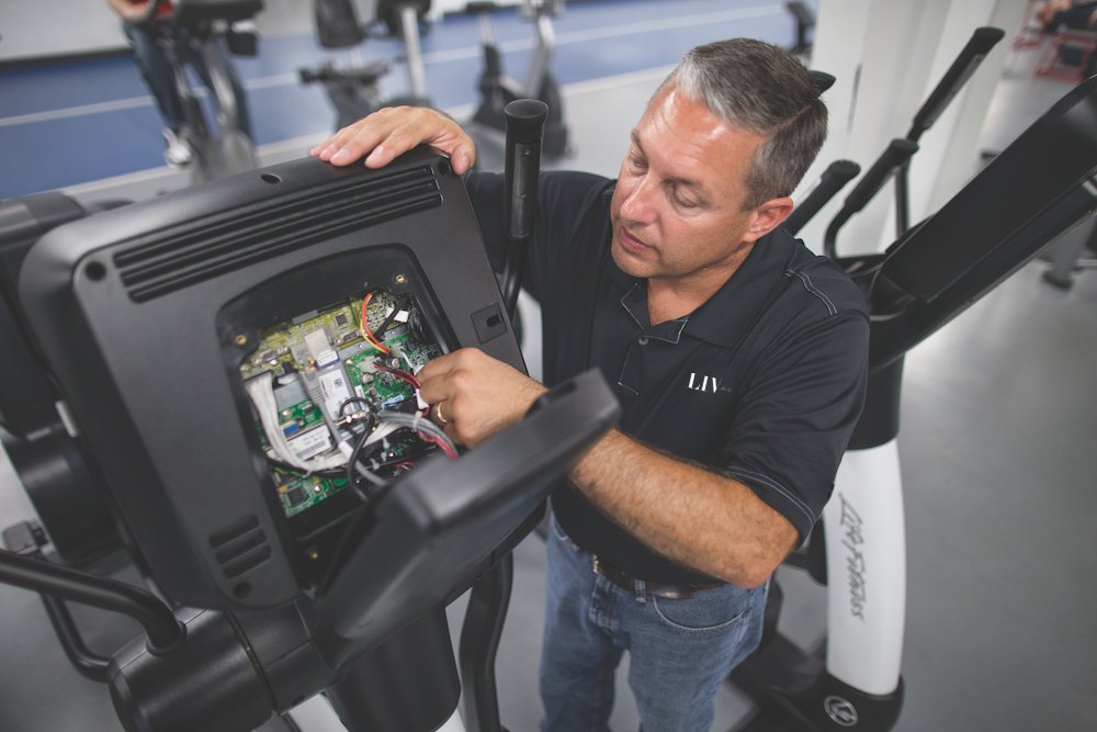 LIV technician servicing the console of a treadmill