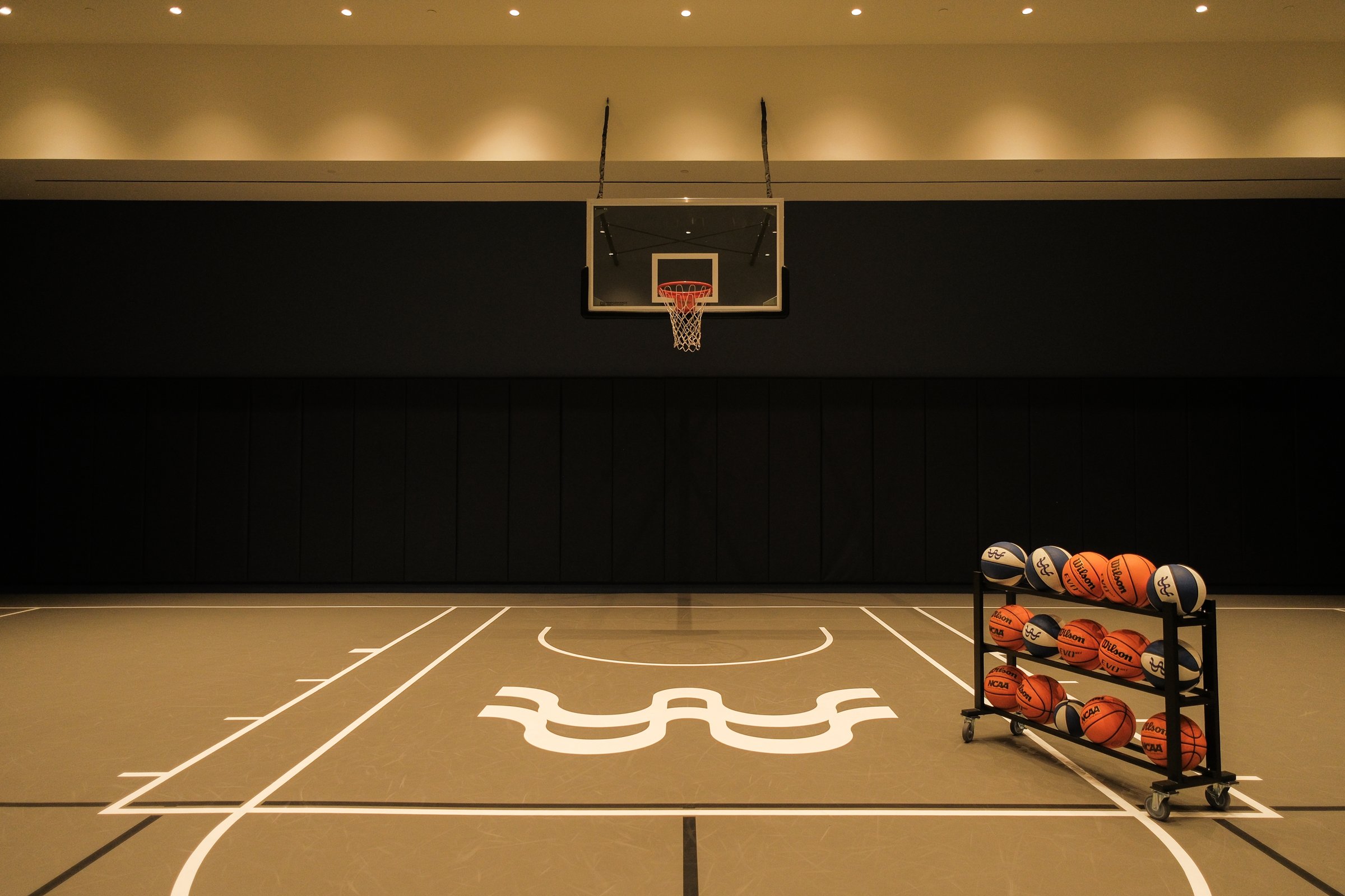 Indoor basketball court with LIV logo and a rack of balls
