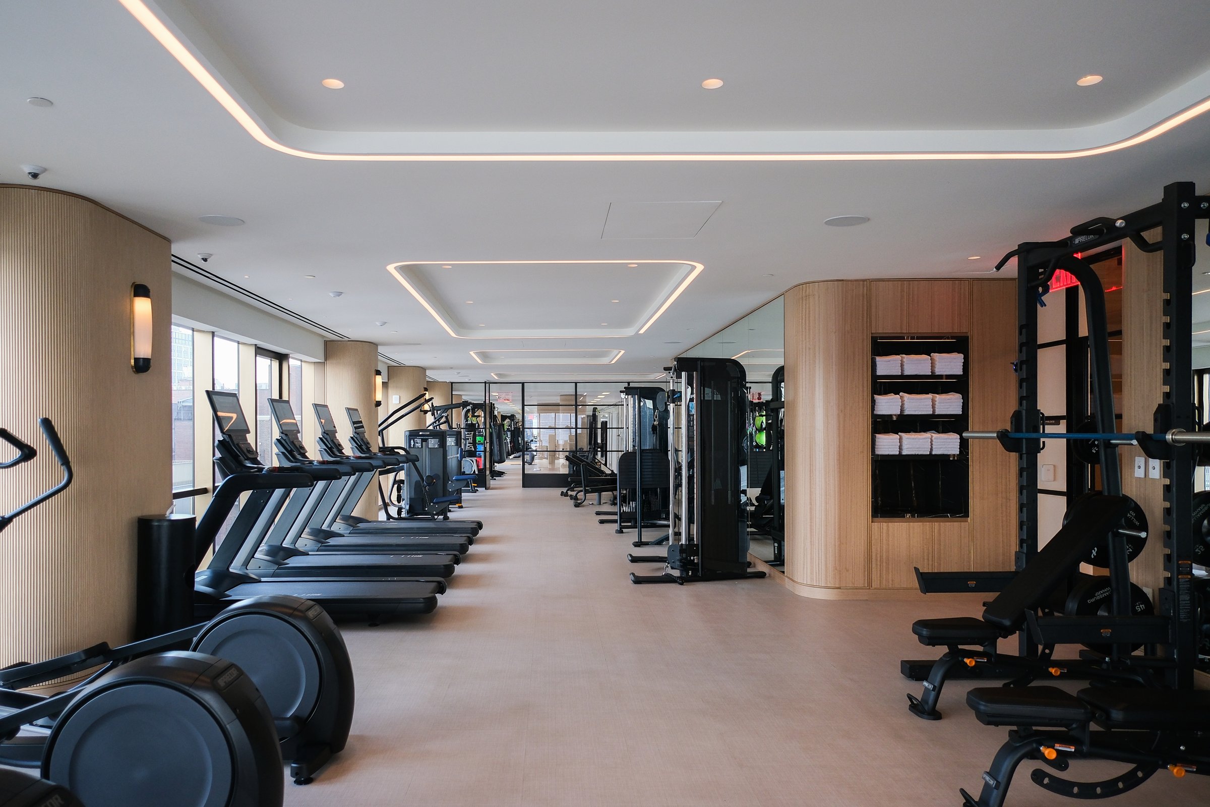 Cardio machines lined up in a bright residential fitness center