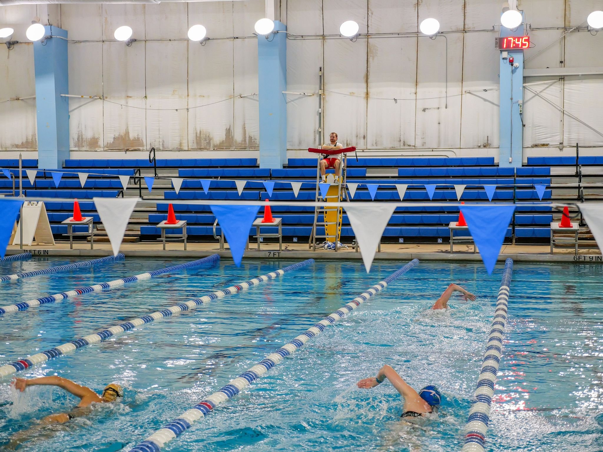 Swimmers in an indoor competition pool with lane flags