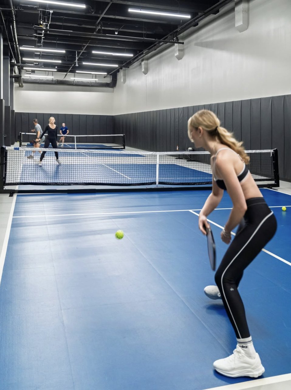 Player serving on an indoor pickleball court