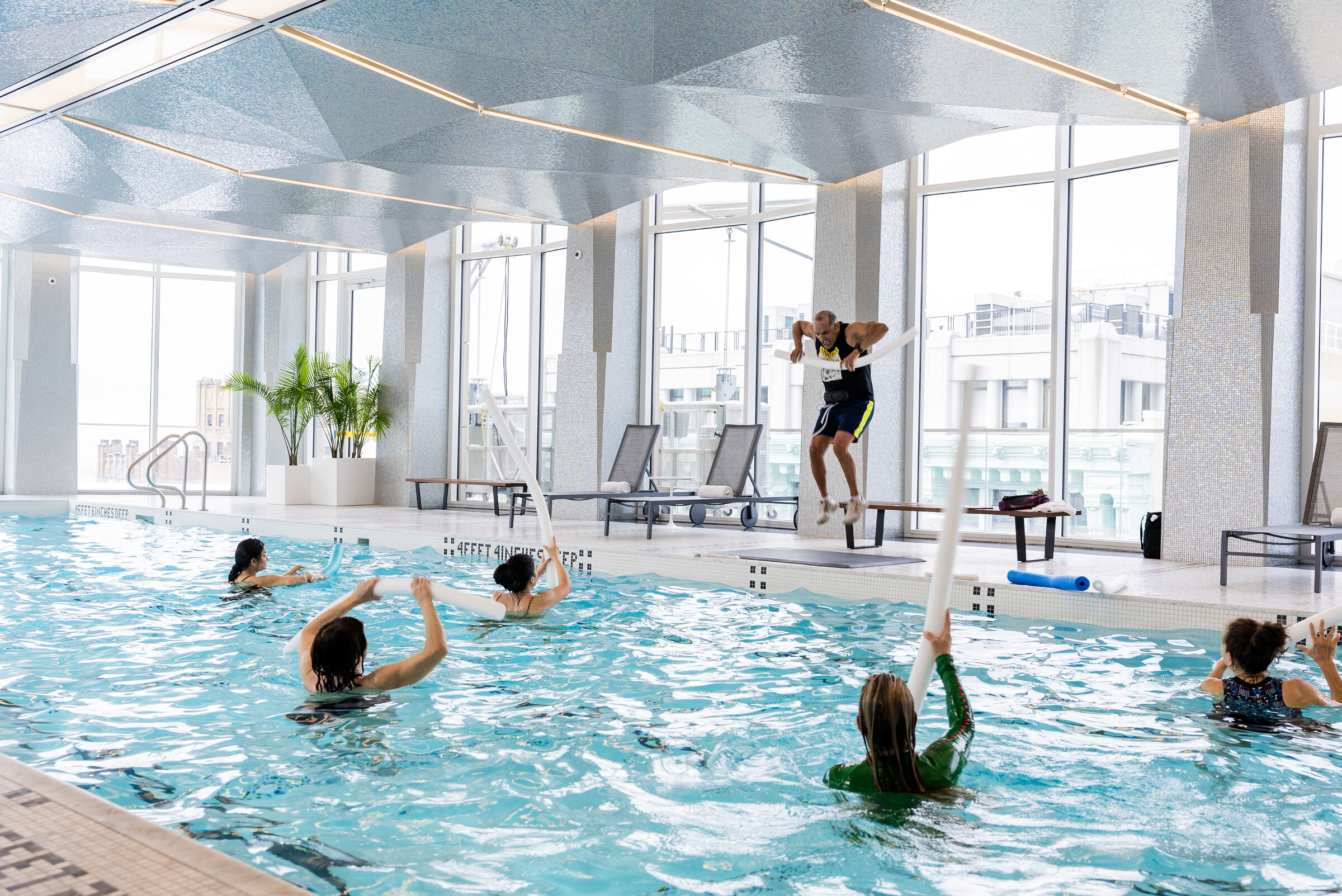 Aqua-fitness class in an indoor pool with an instructor leading from the deck