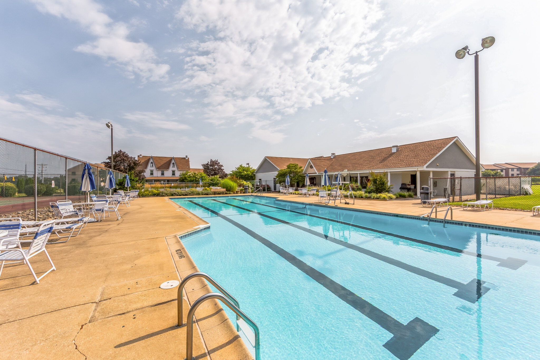 Outdoor community lap pool with loungers and houses in the background