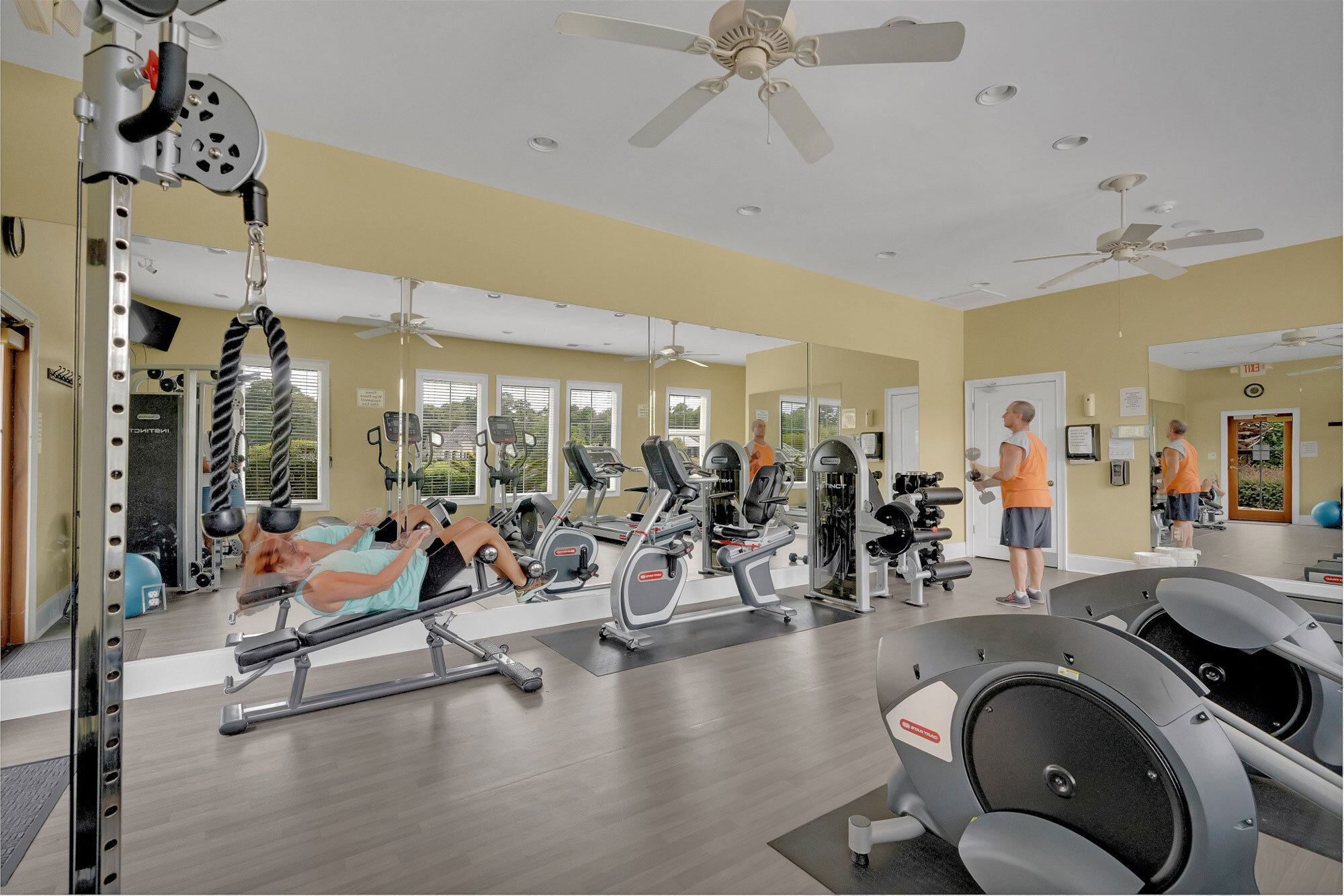 Residents exercising on recumbent bikes and weight machines in a community gym