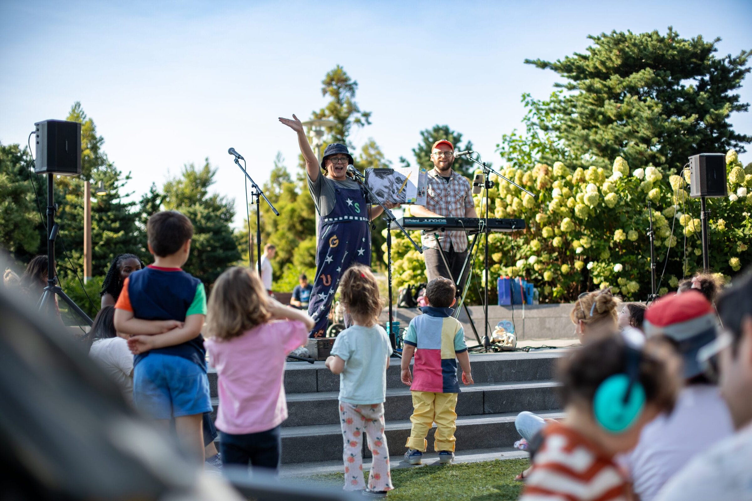 Outdoor performer on a lawn stage with young children watching