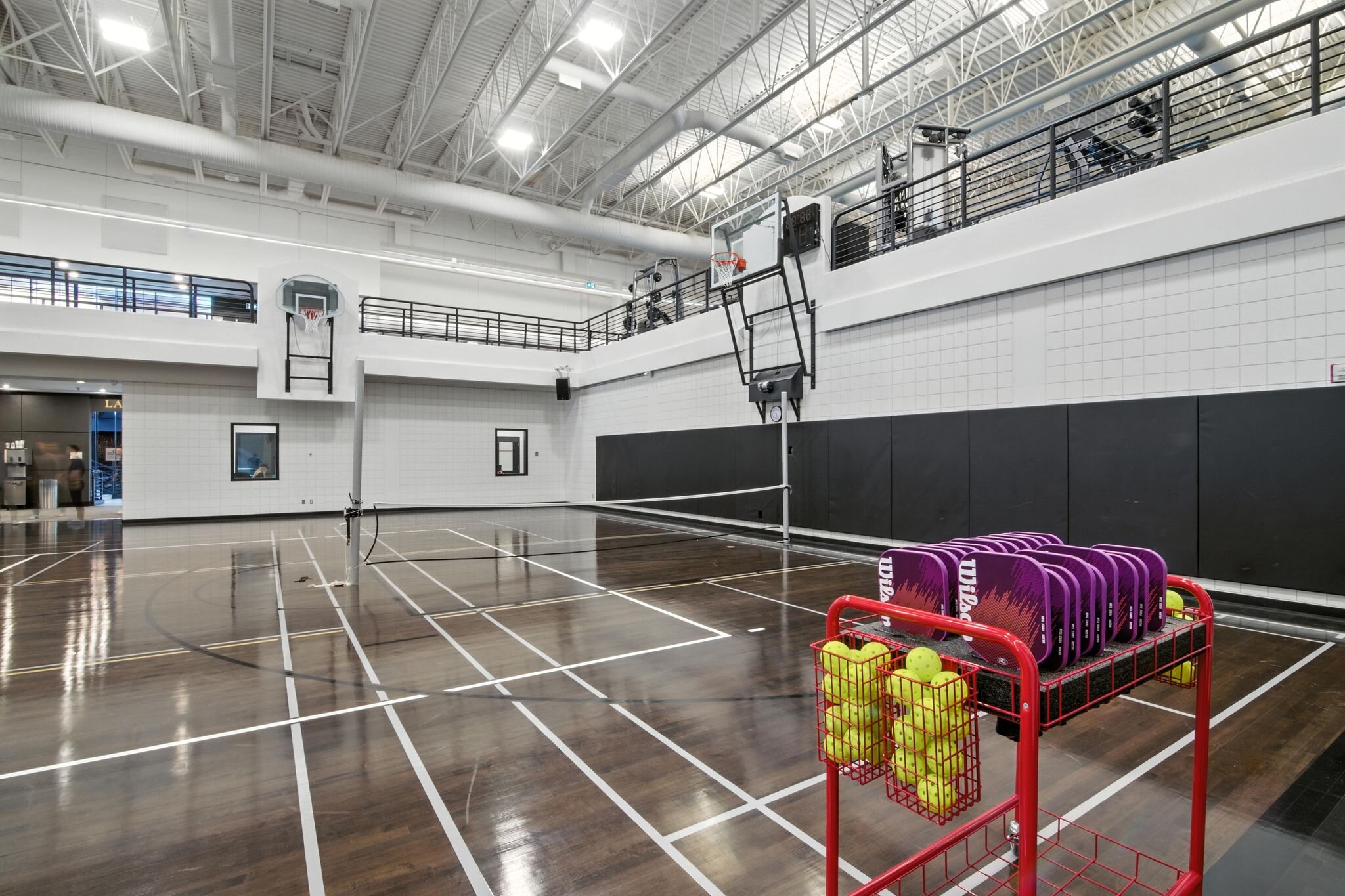 Indoor gymnasium sport court with a basketball hoop and a ball rack