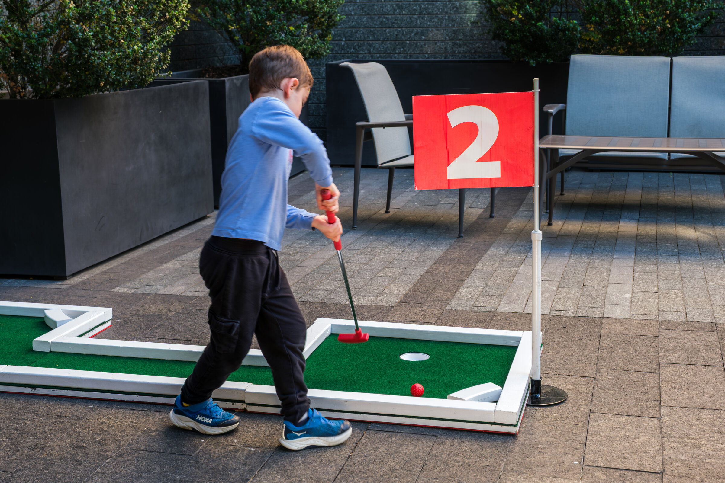 Child playing on an outdoor mini-golf putting course