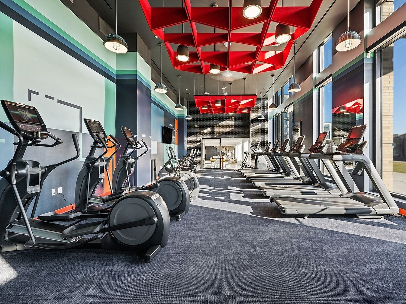 Cardio floor with a row of treadmills under a red ceiling feature