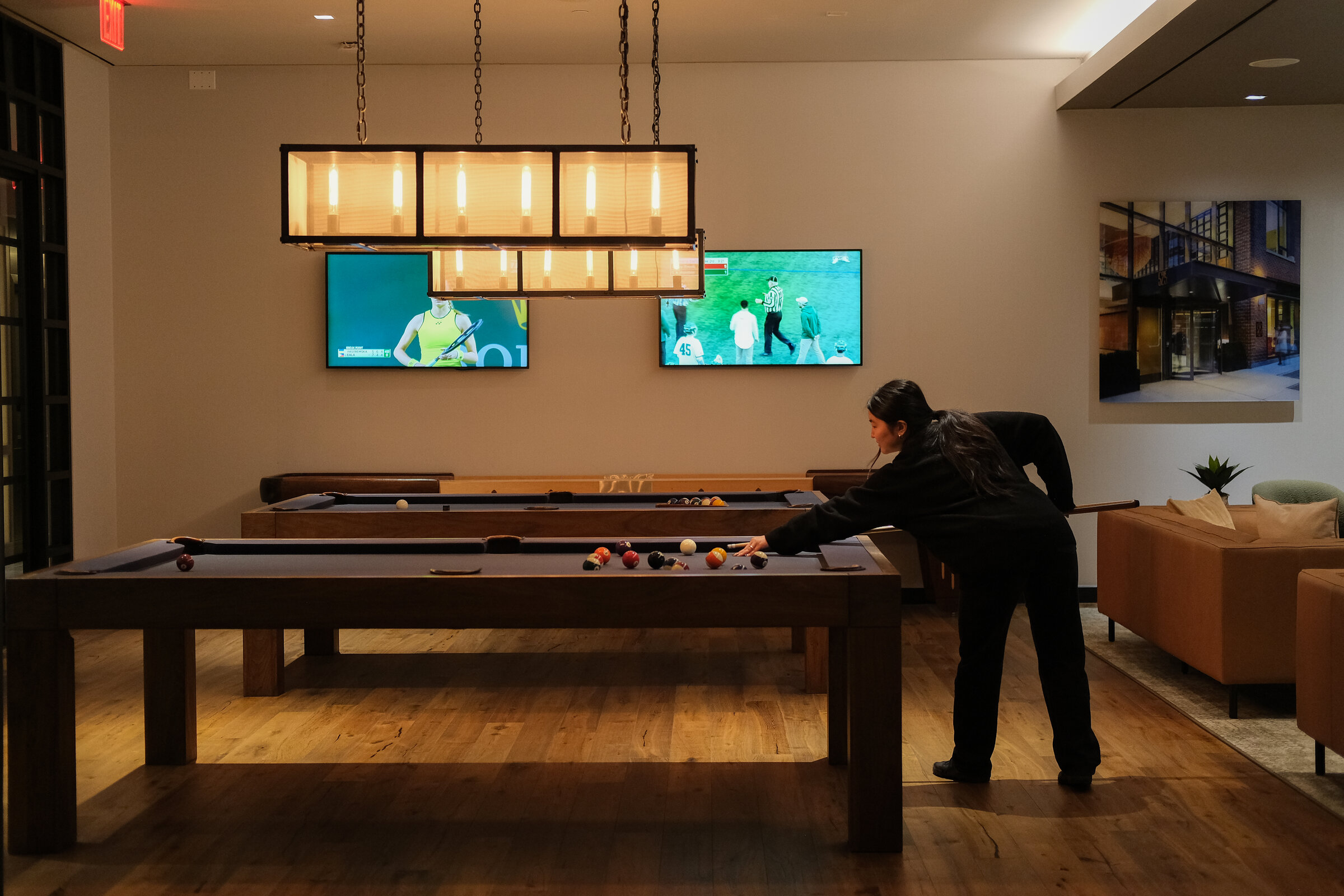 Games room with a shuffleboard table and wall-mounted screens