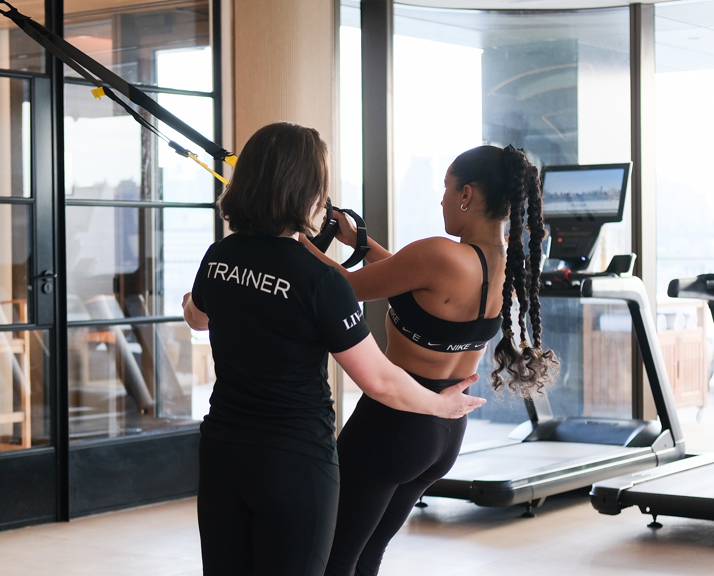 Personal trainer coaching a client on a treadmill in a residential fitness center
