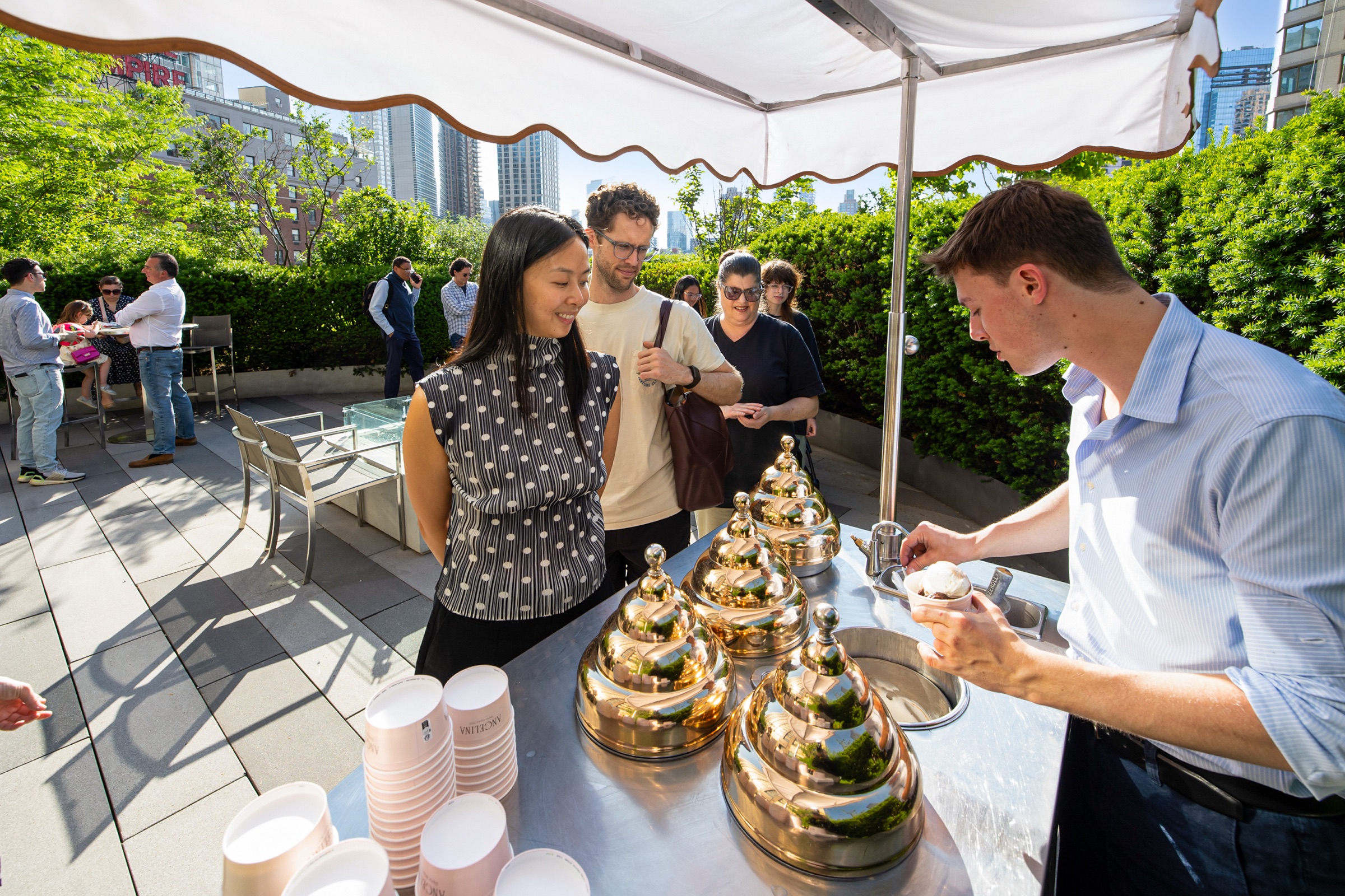 Catered rooftop event with chafing dishes under a striped canopy